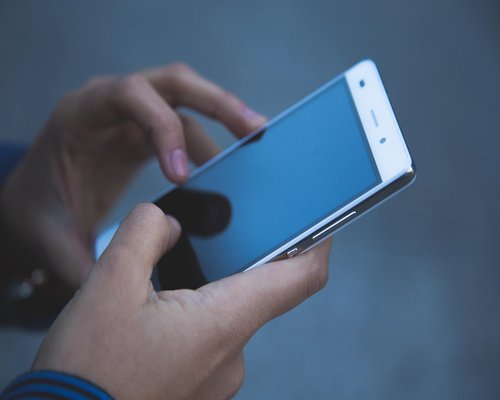 Commuter using a smartphone on public transit with adjusted screen brightness
